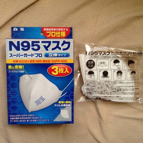 白元の「N95マスク」のパッケージ表と内容物（おもて面）。画面左は、青い箱に立体的なN95マスクの写真が印刷されている。画面右は、黒文字で使用方法や仕様が書かれた透明なビニール袋に、N95マスクが1つ折り畳まれた状態で入っている。
