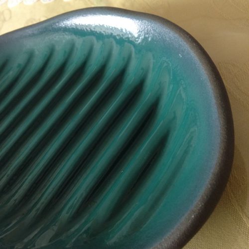 電子レンジで魚が焼けるふしぎなお皿（小判型）に近づいて撮影した写真。青緑色の皿に溝が何本もついている。