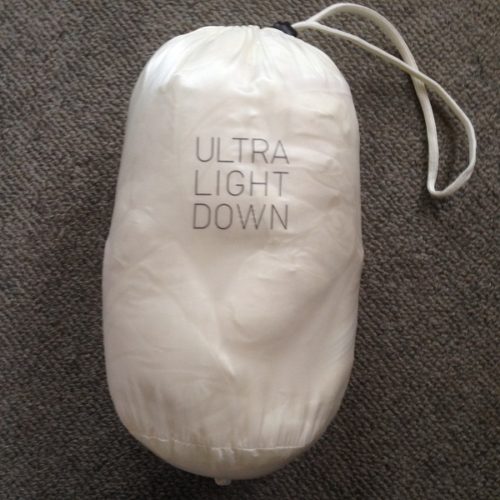 UNIQLOの白色のダウンベストSサイズを白い袋に収納し、正面から撮影した写真。「ULTRA LIGHT DOWN」のロゴが袋の正面にプリントされている。