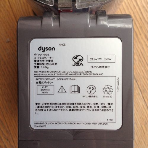 布団掃除機Dyson V6 Triggerの底面を撮影した写真。底面に、重さや充電時間や使用上の注意などが明記されているシールが貼られている。