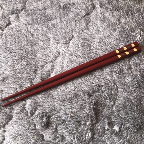 「マザーグースの森」でかつて販売されていたぴよこのお箸を撮影した写真。深紅の短めのお箸が1客写っている。